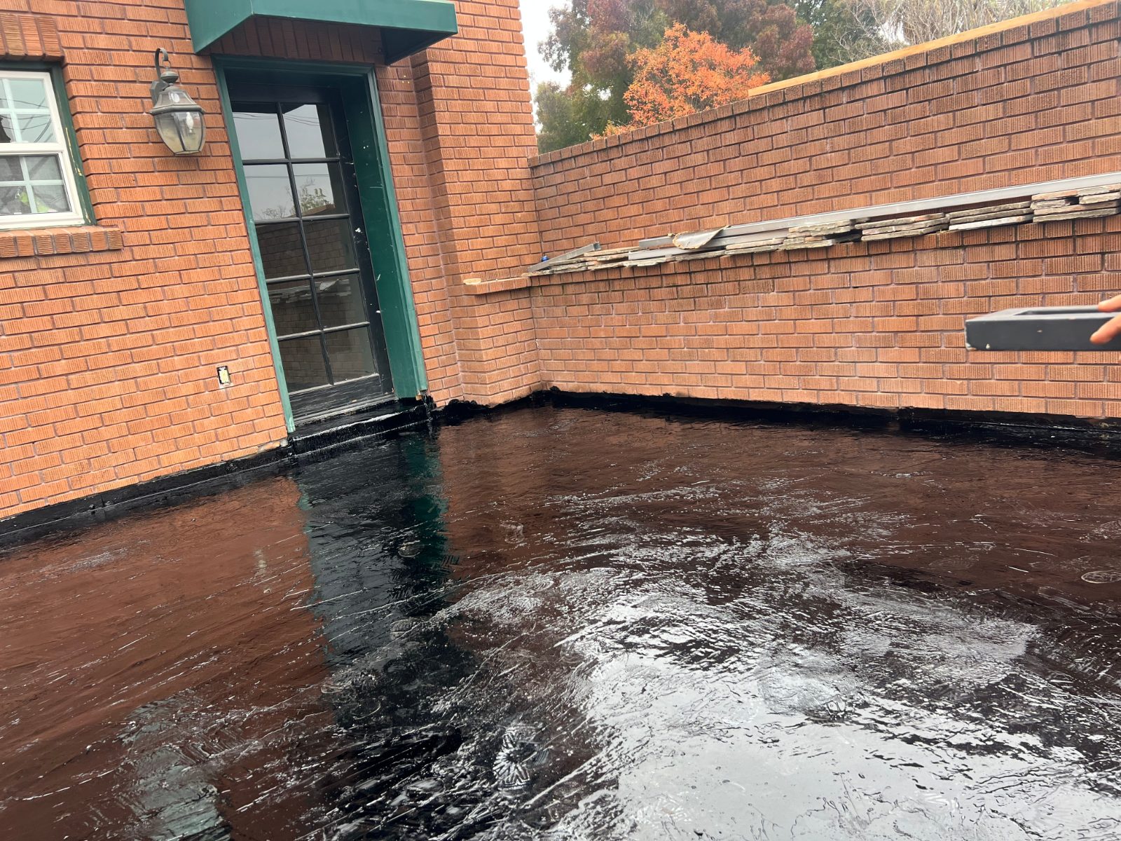 Brick-walled patio waterproofed with black hot mop up to the door threshold and walls.