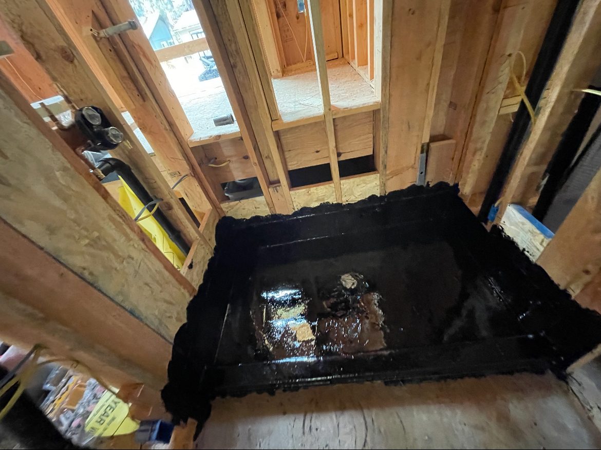 Hot mop waterproofing applied to a shower pan and threshold in a new build.